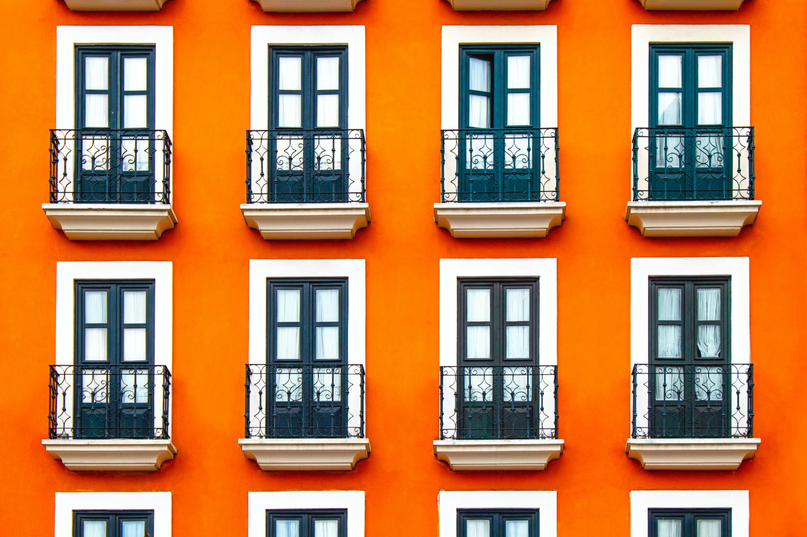 Façade orange à fenêtres et balcons en fer forgé